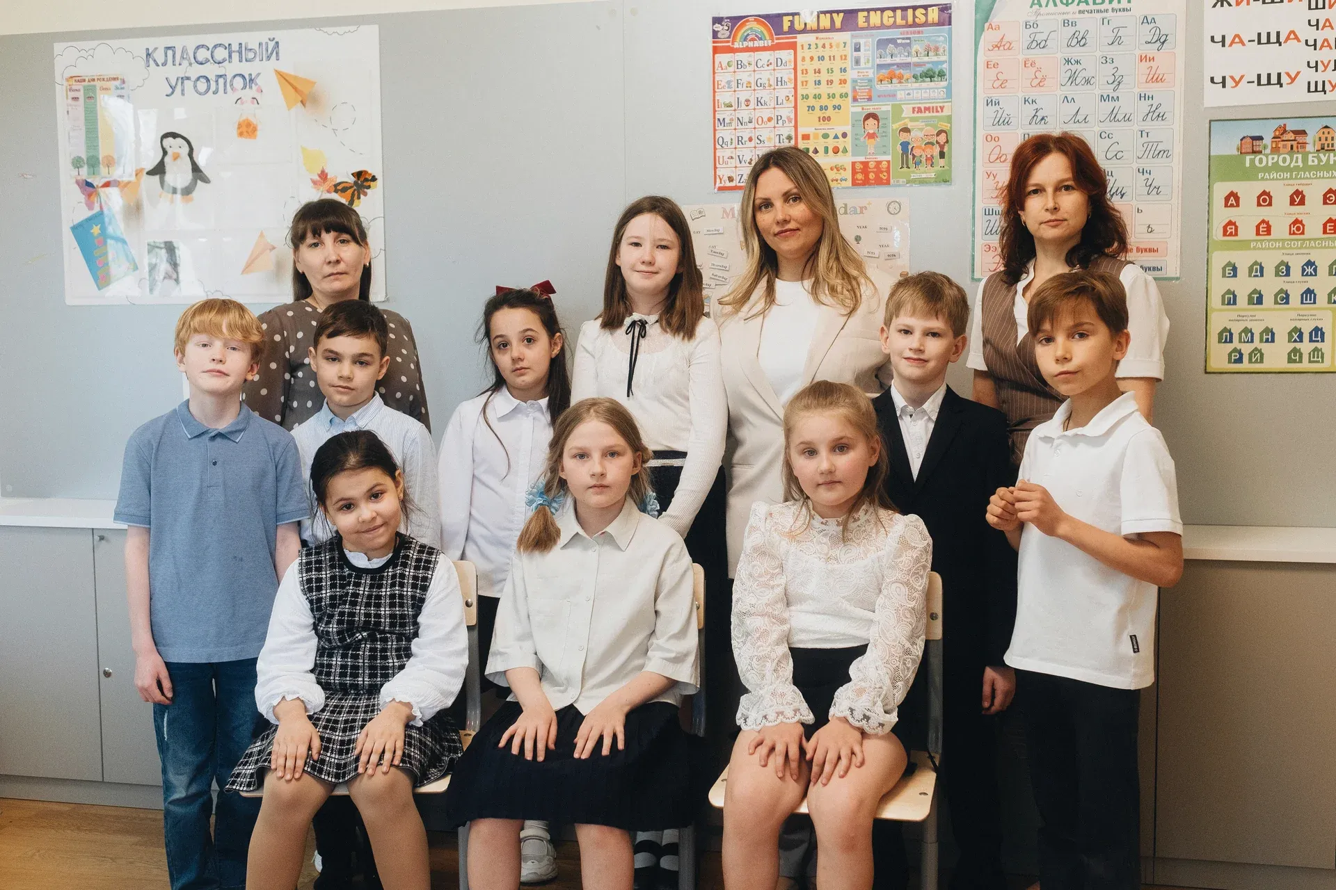 Учитель помогает ученице начальной школы на уроке в частной школе